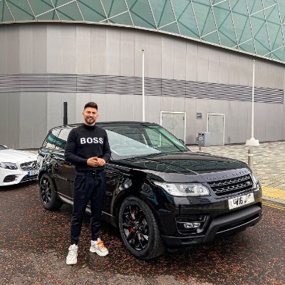 Jake Quickenden posing for a photoshoot while standing in front of his brand new  Range Rover. 